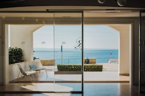 Habitación de hotel moderna con puerta de vidrio que da a un balcón con vistas al mar.