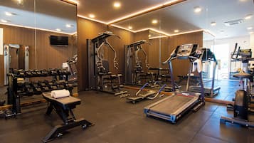 Ein Fitnessstudio mit unterschiedlicher Trainingsausstattung, darunter Laufbänder, Kraftgeräte und Kurzhanteln.