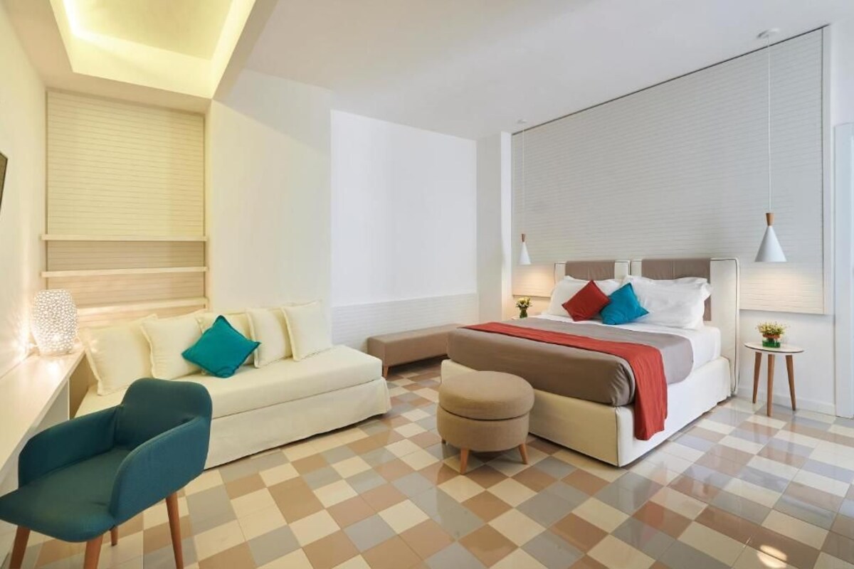 Ein modernes Hotelzimmer mit einem Bett, einem Sofa, einem Schreibtisch und einem Sessel.