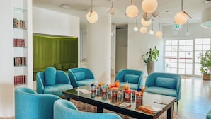 Un salon moderne avec des fauteuils turquoise, une table basse en verre et un mur d’accent vert.