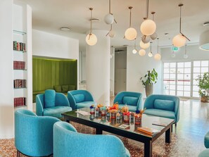 A modern living room with teal armchairs, a glass coffee table, and a green accent wall. - Grand Hotel Riviera CDS Hotels (Nardò)