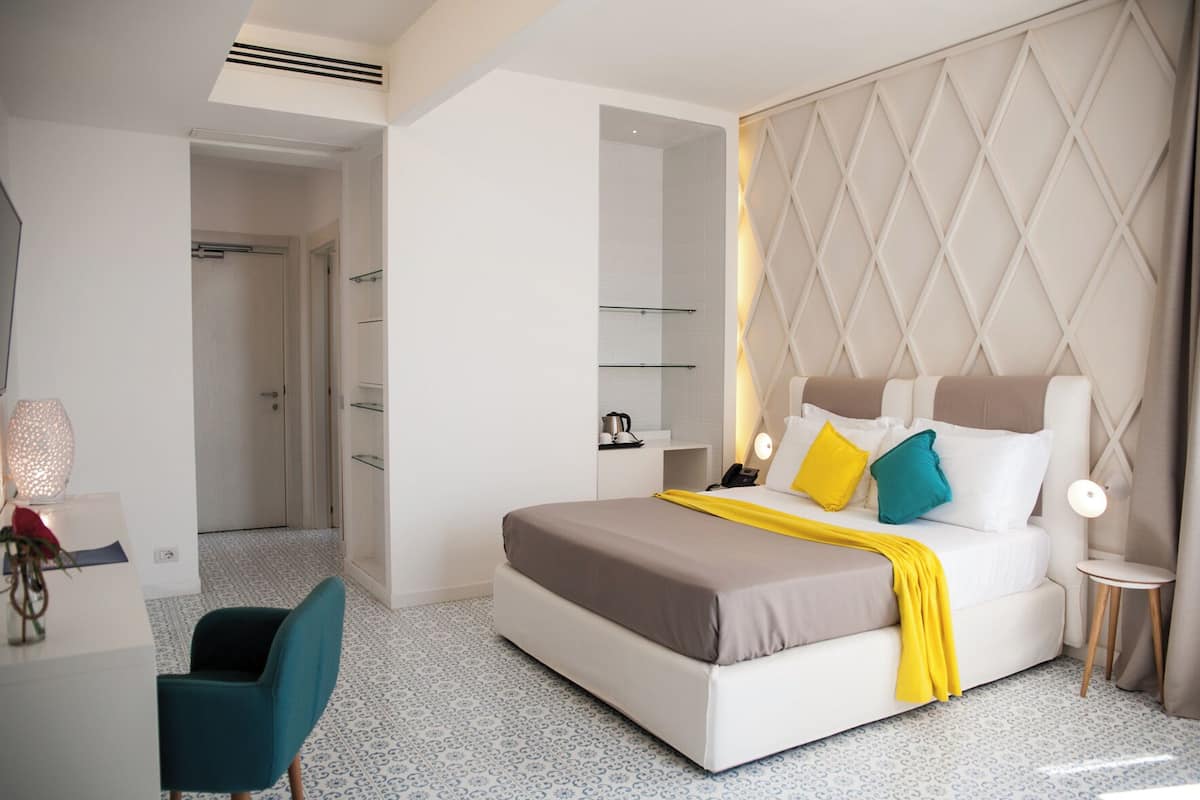 Ein modernes Hotelzimmer mit Bett, Nachttisch, Stuhl und Kleiderschrank.