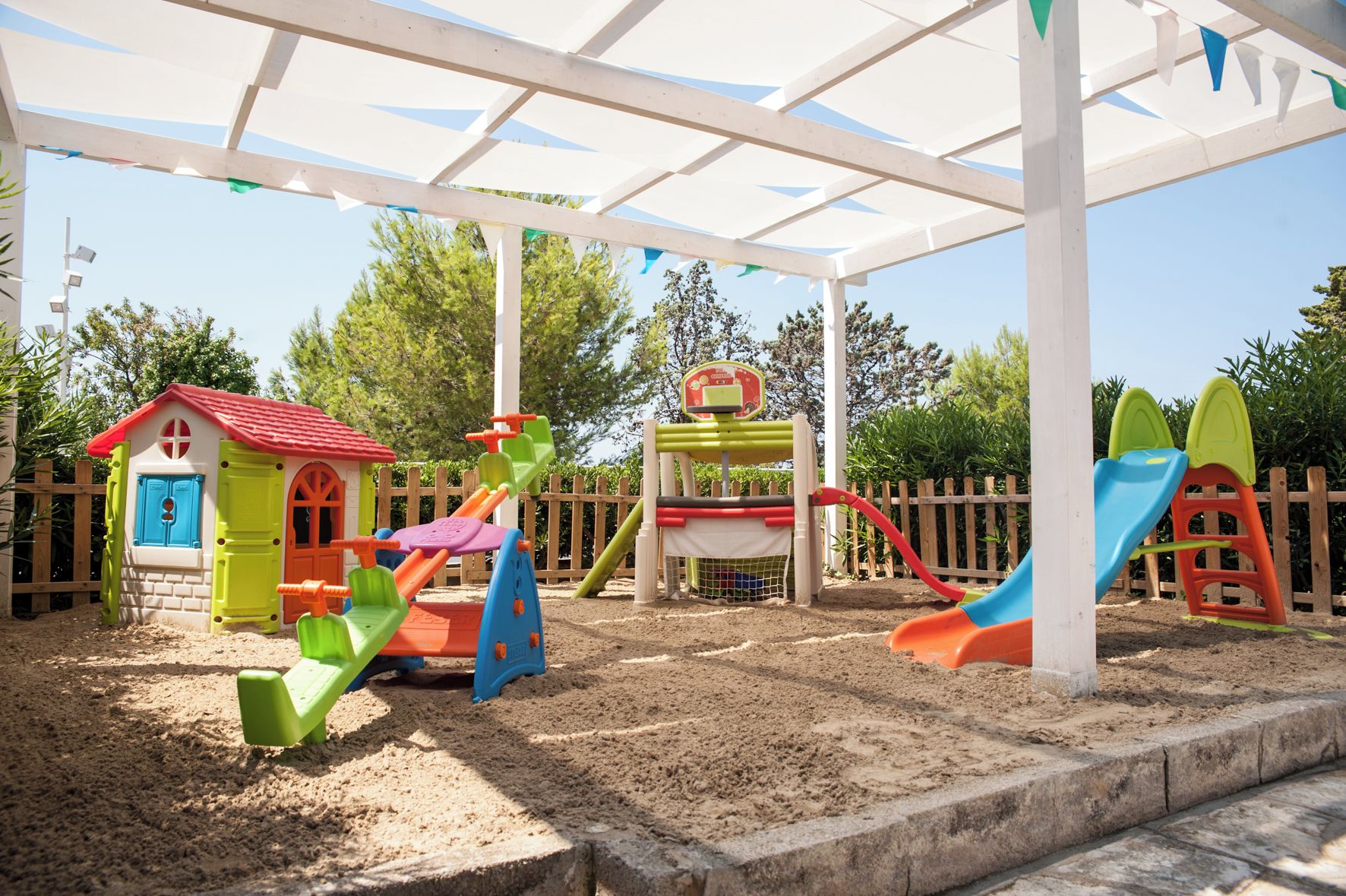 A children's play area with a sandpit, a small house, and a slide.