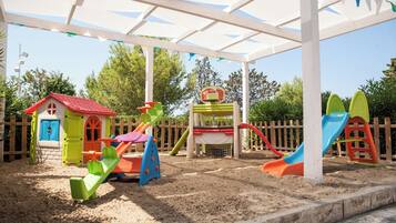 A children's play area with a sandpit, a small house, and a slide.