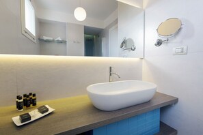 A modern bathroom with a large oval sink, a mirror, and a shelf with toiletries. - Grand Hotel Riviera CDS Hotels (Nardò)