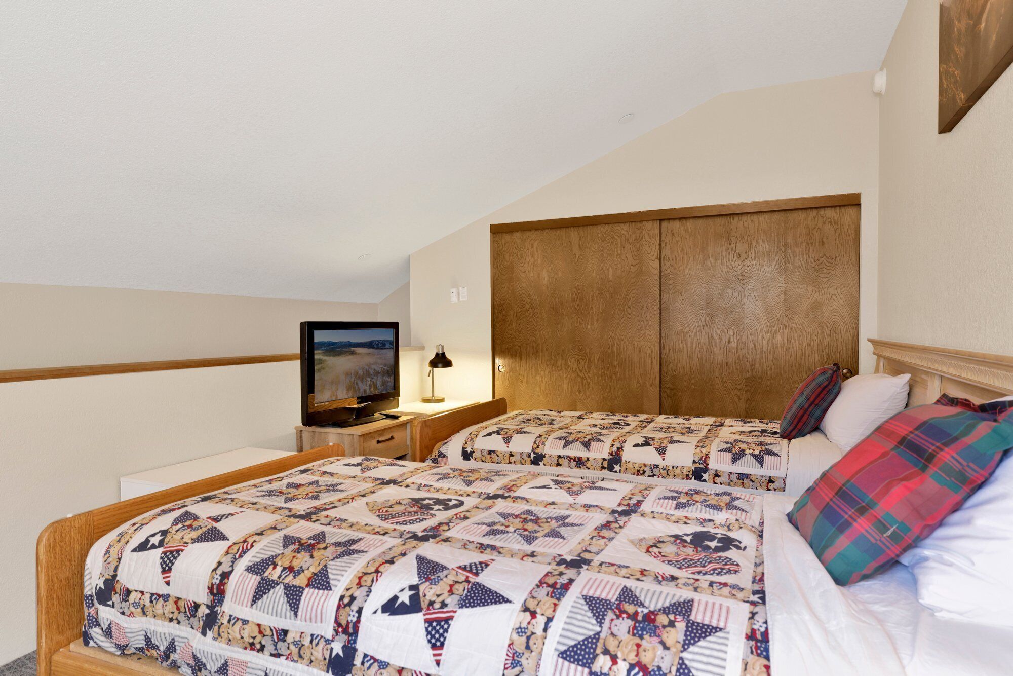 Un dormitorio con dos camas, un televisor y un cabecero de madera.