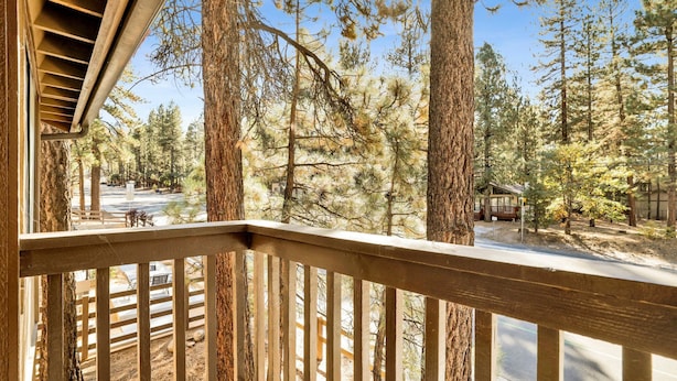 A wooden balcony with a view of a forested area and a road. - Summit Ski and Bike Trails #2574 (Big Bear Lake)