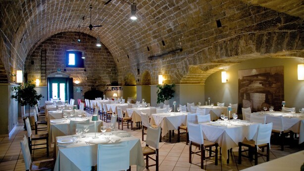 A restaurant with multiple tables set for dining, featuring a brick ceiling and stone walls. - Masseria Zanzara (Presicce-Acquarica)