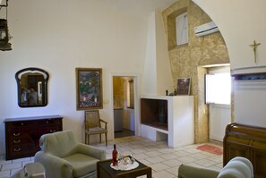 Ein Wohnzimmer mit Kamin, einer Couch, einem Sessel, einem Holzkabinett und einem Spiegel.