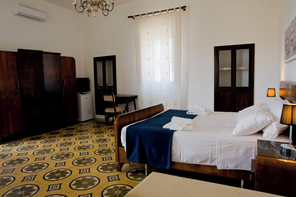 Een hotelkamer met een bed, een bureau, een stoel, een kledingkast en een spiegel.
