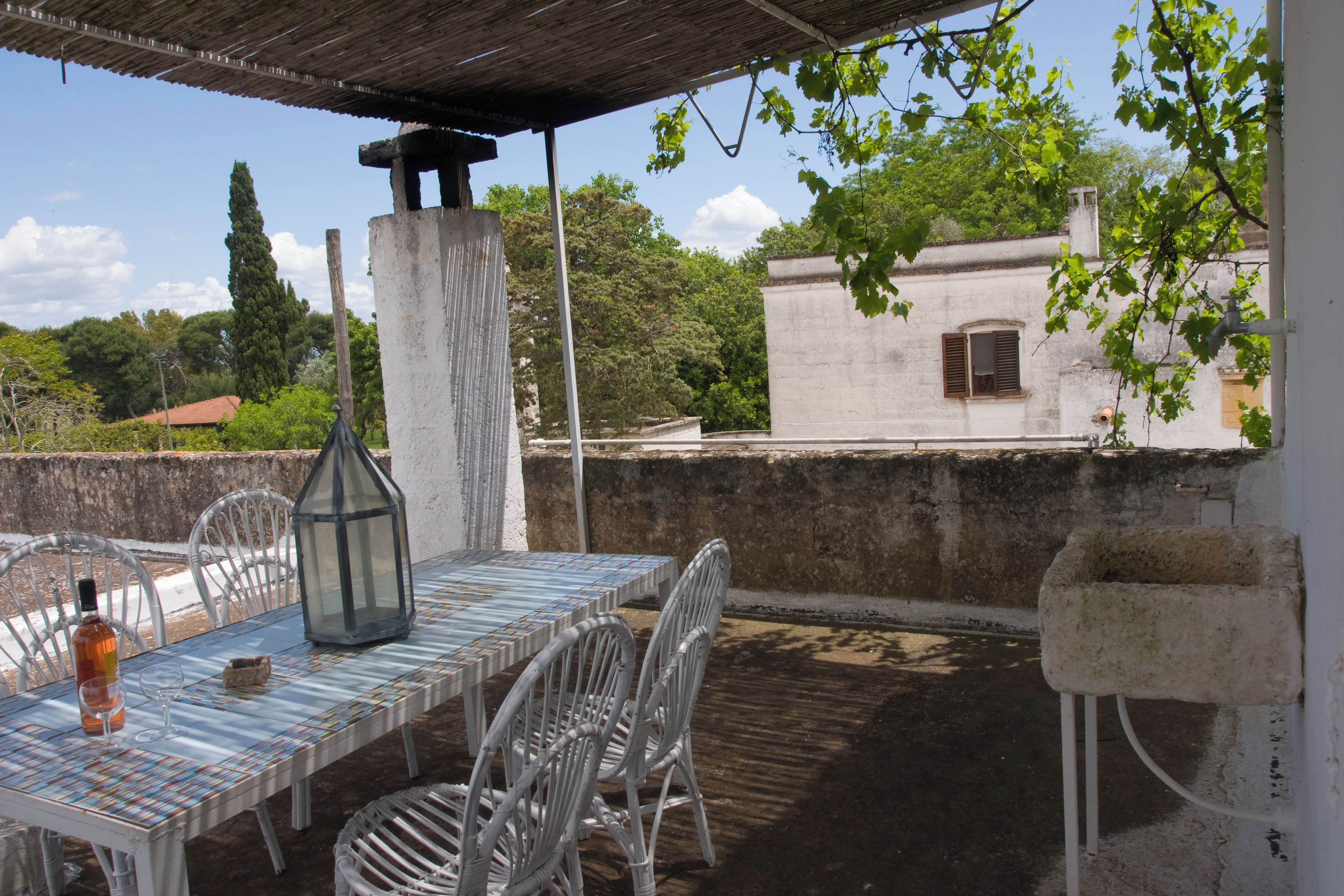 An outdoor patio with a table and chairs, a bottle, and a lantern.