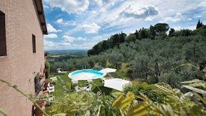 A pool area with a clear view of the surrounding landscape, including trees and distant hills. - Casa Lari (San Gimignano)