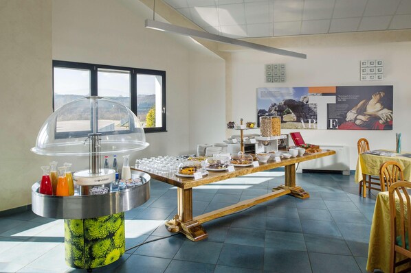 Un buffet proposant une variété de plats et de boissons, une grande fenêtre offrant une belle vue et un mur orné d’affiches informatives.