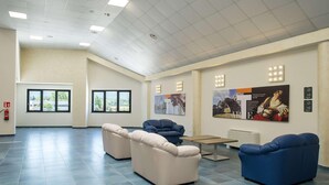 A spacious lobby with a high ceiling, large windows, and a fire extinguisher on the wall. - Testani Colleferro (Colleferro)