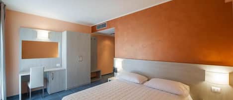 Quarto com cama, mesas de cabeceira, escrivaninha e guarda-roupa.