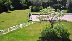 Un jardin bien entretenu, avec un chemin de pierres, des haies soigneusement taillées et une variété d’arbustes.