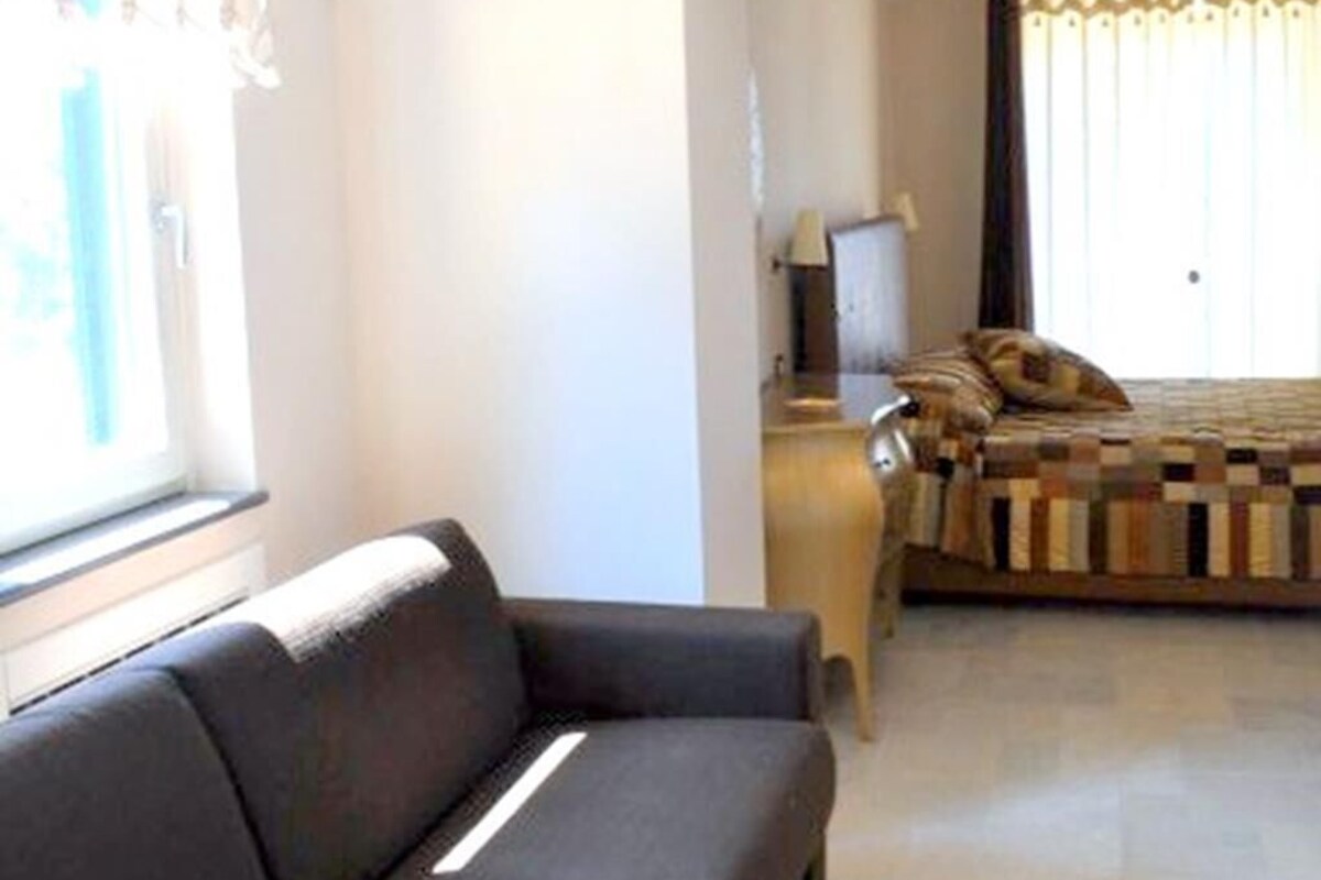 A living room with a sofa, a small table, and a bed with a patterned bedspread.