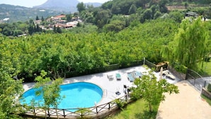 Une piscine entourée d’une végétation luxuriante, avec une chaîne de montagnes en toile de fond.