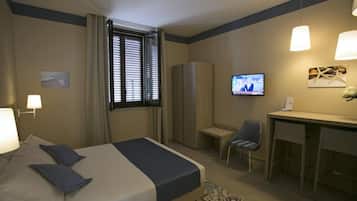 A hotel room with a bed, a desk, a chair, a television, and a wardrobe.