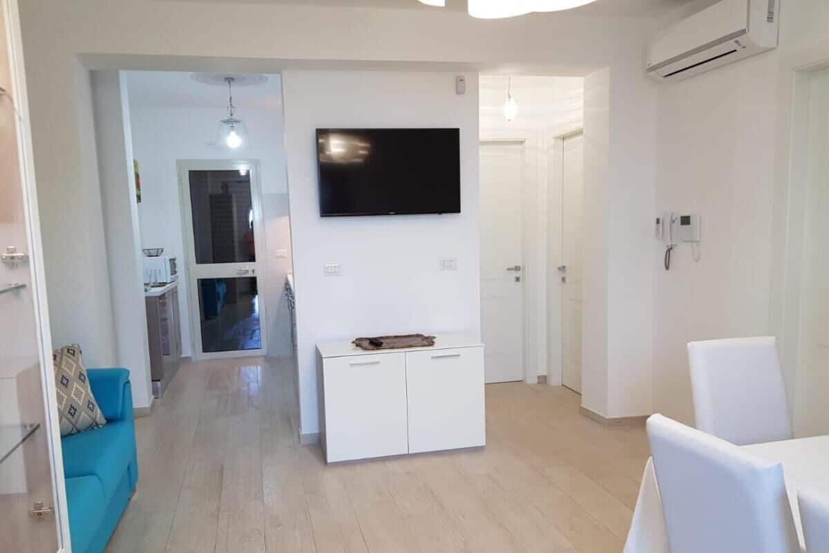 A modern living room with a flat-screen TV, a white cabinet, and a blue sofa.