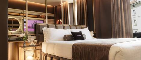 Ein modernes Hotelzimmer mit einem großen Bett, einem Nachttisch mit Lampe und einem großen Spiegel.