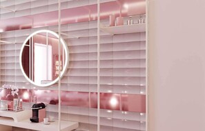 Een badkamer met een wastafel, een ronde spiegel met verlichting, en een plank met toiletartikelen.