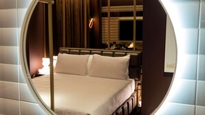 A circular window view of a hotel room with a bed, a bedside table, a lamp, and a mirror. - Odsweet Duomo Milano Hotel (Milan)