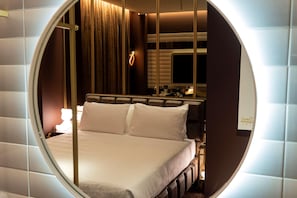 A circular window view of a hotel room with a bed, a bedside table, a lamp, and a mirror. - Odsweet Duomo Milano Hotel (Milan)