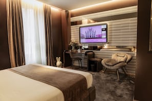 Een hotelkamer met een groot bed, een bureau met een computer, een stoel en een aan de muur bevestigde televisie.