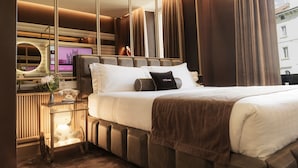 Een moderne hotelkamer met een groot bed, een nachtkastje met een lamp en een grote spiegel.