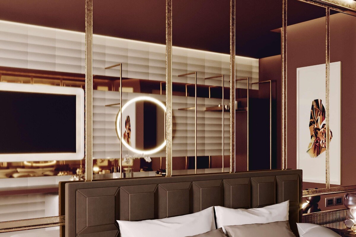 Een moderne hotelkamer met een groot bed, een televisie, een spiegel en een decoratief kunstwerk aan de muur.