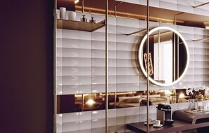Een moderne badkamer met een grote spiegel, een wastafel met toiletartikelen en een decoratieve vaas.