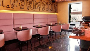 Een restaurant met roze zitplaatsen, een bloemendecor aan het plafond en een taartvitrine.