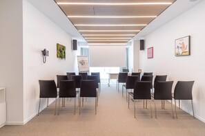 A conference room with rows of black chairs, a whiteboard, and a projector screen. - Innside Milano Torre Galfa (Milan)