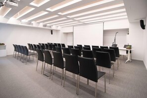 A conference room with rows of black chairs, a whiteboard, and a projector. - Innside Milano Torre Galfa (Milan)