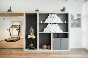 Ein modernes Zimmer mit Laufband, einer Aufbewahrungseinheit mit ordentlich gerollten Handtüchern und einem Basketball.
