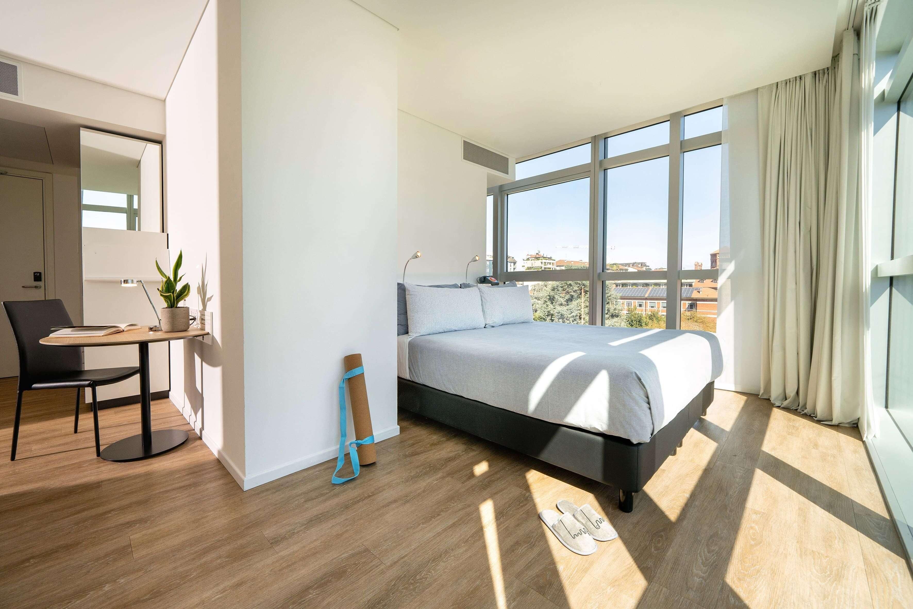 A modern bedroom with a large bed, a desk, and a chair.