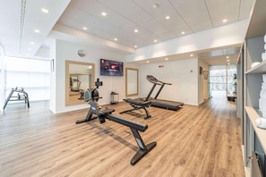 A modern gym with exercise equipment, a large mirror, and a television screen. - Innside Milano Torre Galfa (Milan)