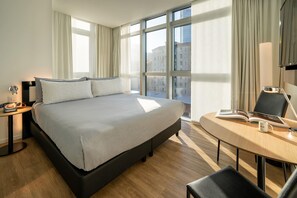 A hotel room with a large bed, a desk with a chair, a telephone, and a window with curtains. - Innside Milano Torre Galfa (Milan)
