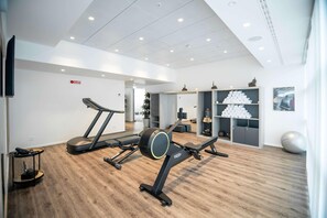 Un gimnasio moderno con cintas de correr, una prensa de pesas y una pelota de ejercicios grande.