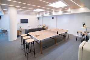 A modern conference room with a large table, several stools, a TV screen, and a whiteboard. - Innside Milano Torre Galfa (Milan)
