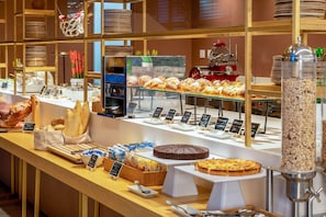 A bakery display with various baked goods and a coffee machine. - Innside Milano Torre Galfa (Milan)