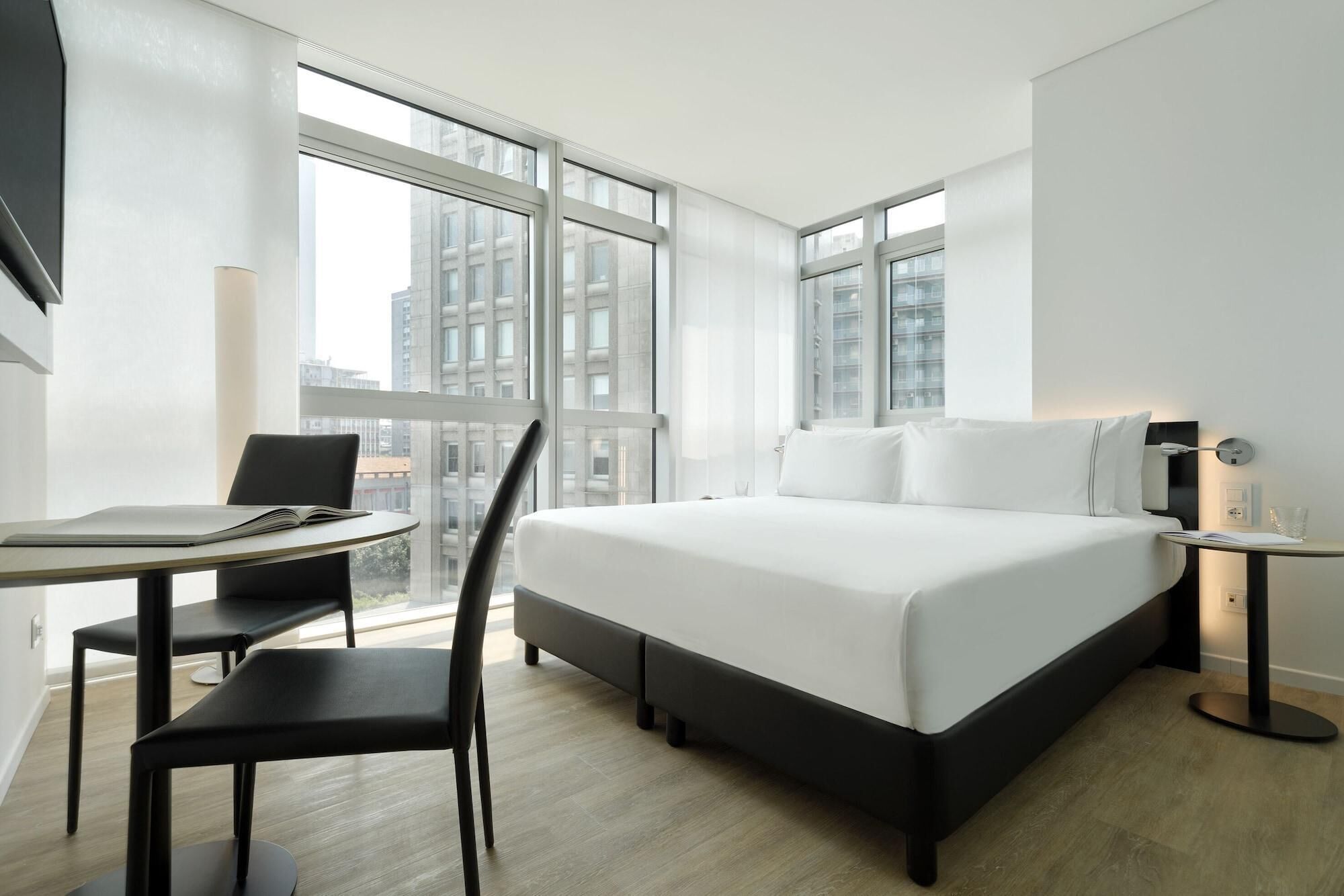 A modern hotel room with a large bed, a desk, and a chair.