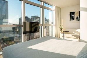 A hotel room with a large bed, a flat-screen TV mounted on the wall, a small table with a plant, and a view of the cityscape through large windows. - Innside Milano Torre Galfa (Milan)