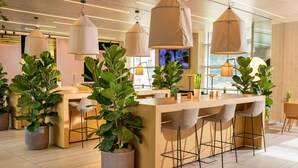 Uma área de bar moderna com balcões de madeira, várias luminárias pendentes e plantas em vasos.
