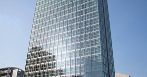 Un grand immeuble moderne, entièrement vitré, dont la façade est constituée d’une grille de fenêtres.
