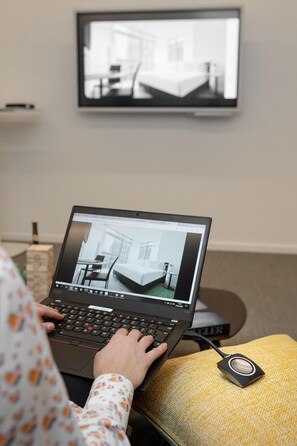 A person using a laptop with a view of a hotel room on the screen. - Innside Milano Torre Galfa (Milan)