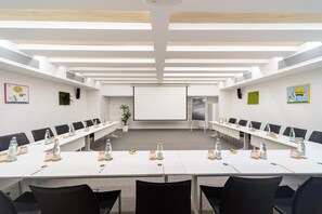 A conference room with a long table, black chairs, and a projector screen. - Innside Milano Torre Galfa (Milan)