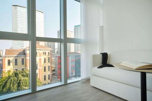 Een moderne kamer met grote ramen, een witte bank en een tafel met een open boek.