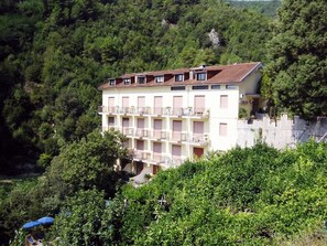 A multi-story building with balconies, surrounded by dense greenery.